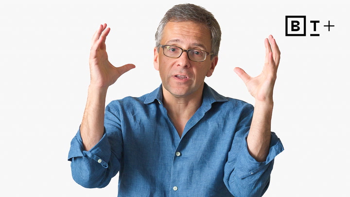 A man in glasses and a blue shirt gestures with both hands raised. A "B T +" logo appears in the upper right corner on a plain white background.