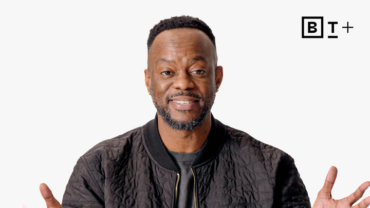 A man wearing a black quilted jacket stands in front of a plain white background with the BT+ logo in the top right corner.