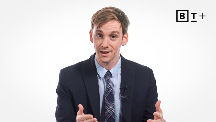 A man in a suit and tie speaks while gesturing with his hands; a "BT+" logo appears in the top right corner on a white background.