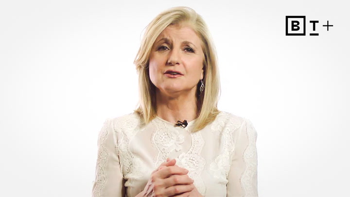 A woman with shoulder-length blonde hair, wearing a white lace top, stands against a plain white background with a “B T +” logo in the upper right corner.