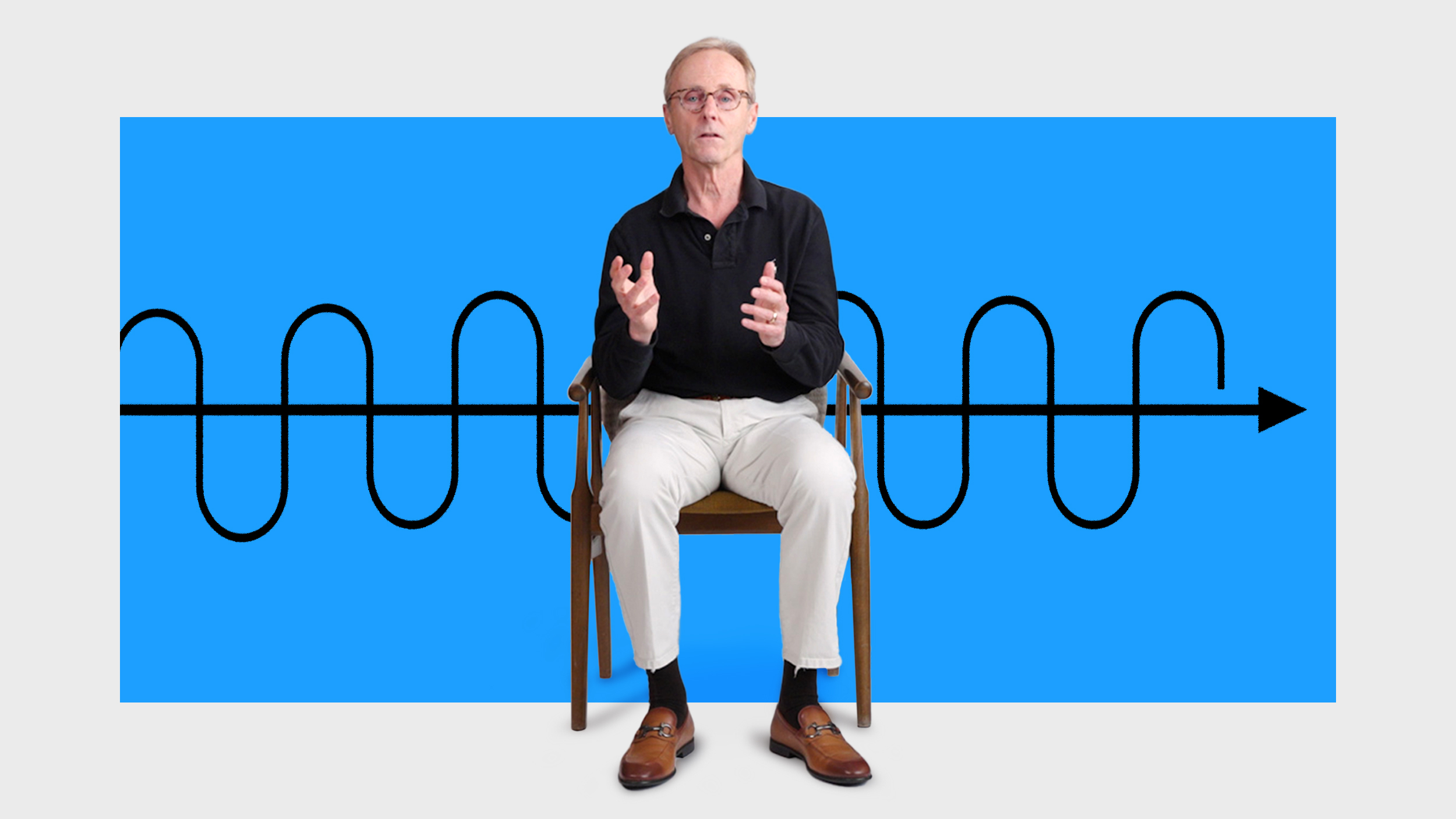 An older man sits on a chair gesturing with his hands in front of a blue background featuring a black sinusoidal waveform and an arrow.
