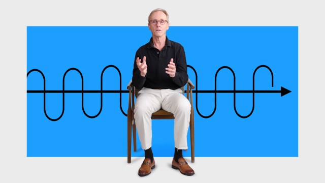 An older man sits on a chair gesturing with his hands in front of a blue background featuring a black sinusoidal waveform and an arrow.