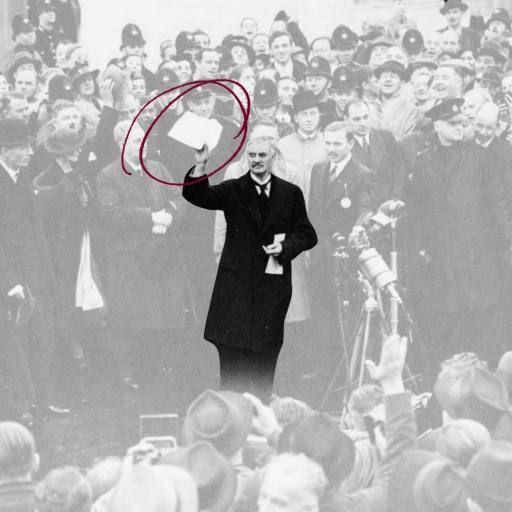 A man in a dark coat holds up a signed document in front of a crowd; the document is circled in red.
