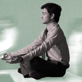Scott Britton, in business attire, sits cross-legged on a desk meditating, while blurred figures move in the background.