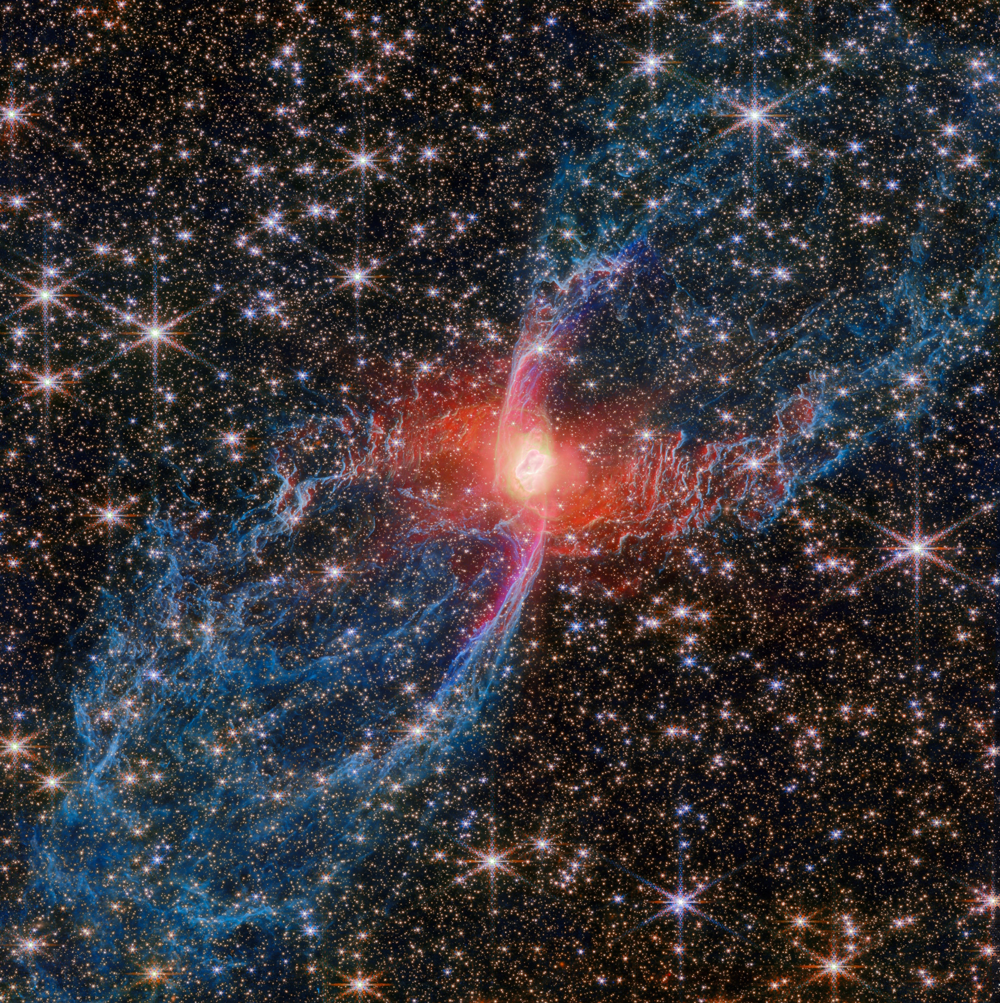 A nebula with a bright red center and blue wisps extends outward, surrounded by numerous stars against a dark background.